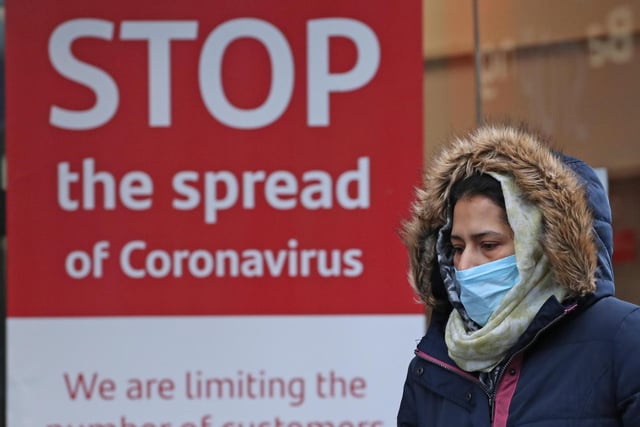 A woman walks past a coronavirus sign in Glasgow