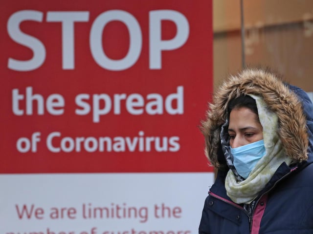 A woman walks past a coronavirus sign in Glasgow