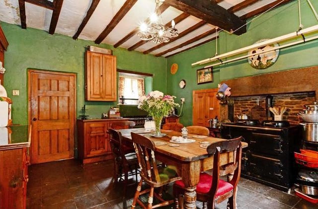 The kitchen has a heavy beamed ceiling, an original gritstone fireplace with stone back, and a two-oven gas-fired Aga range.