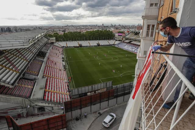 A soccer supporter watches the second-division game match between Rayo Vallecano and Albacete  from a balcony in Madrid, Spain, where football has also returned behind closed doors: Manu Fernandez
