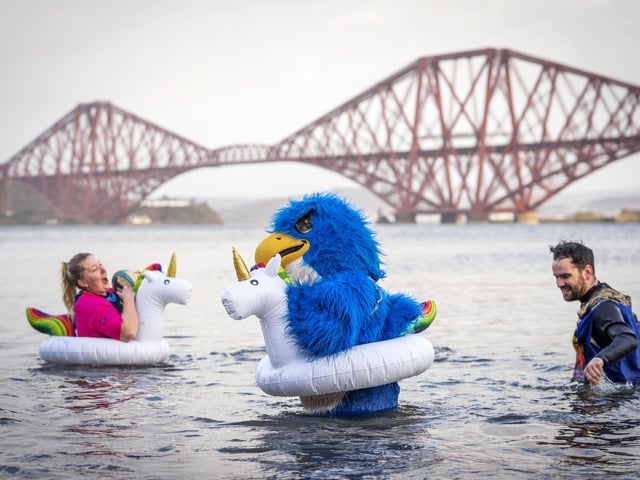 People take part in a New Year's Day dip in front of the Forth Bridge at South Queensferry, Edinburgh. Covid restrictions across Scotland have meant that many new year traditions including the official annual Loony Dook have been cancelled. Picture date: Saturday January 1, 2022. PA Photo. Photo credit: Jane Barlow/PA Wire