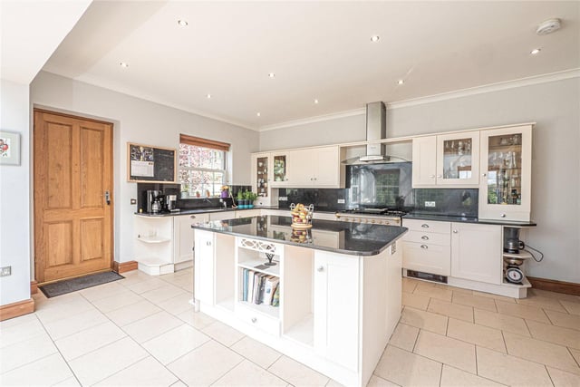 The stylish kitchen is bright and airy, with Shaker-style units, granite worktops, a range cooker and a central island.