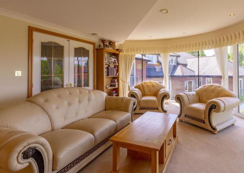 Another view of the warm and homely living room with its curved windows. Ideal for relaxing after a meal.