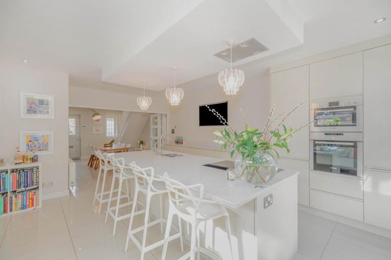 The kitchen island has an integrated seating area with runs its full length with additional storage cupboards beneath. It has deep pan draws and a double stainless steel sink inset into the work surface. Incorporated into the island unit are a washing machine and a dish washer.