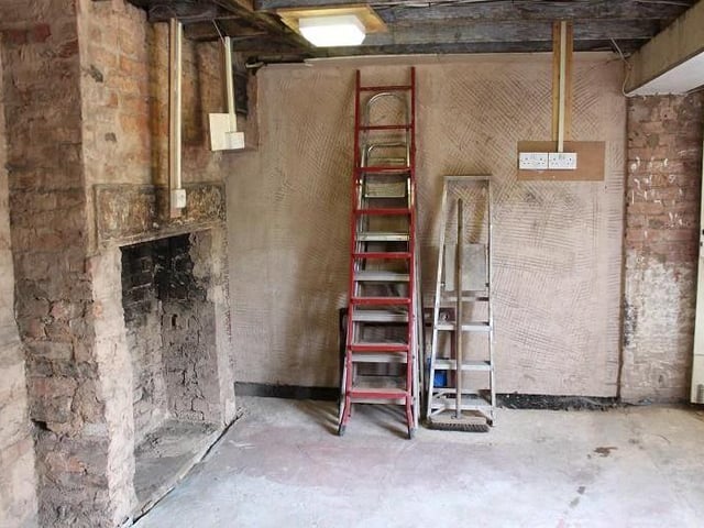 A brick-built fireplace is the main feature of the dining room. A window gives lots of light, and stairs rise to the first floor.