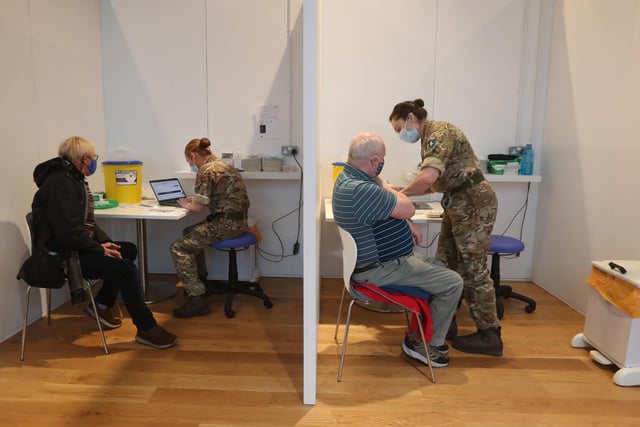 Michael Maddocks (left) and James Logan, both from Edinburgh, receive their coronavirus vaccine from military personnel.