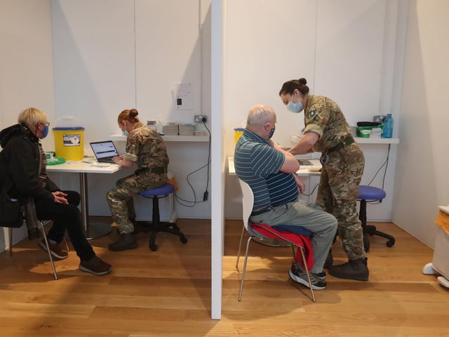 Michael Maddocks (left) and James Logan, both from Edinburgh, receive their coronavirus vaccine from military personnel.