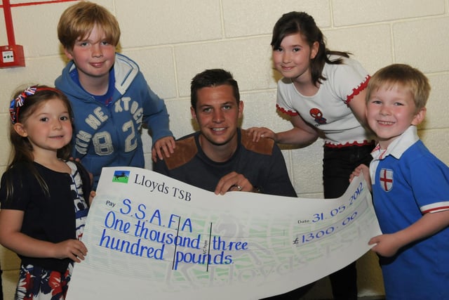 Andrew Garthwaite receives a cheque on behalf of SSAFA from Bede Burn Primary School pupils eight years ago. Who remembers this from 2012?