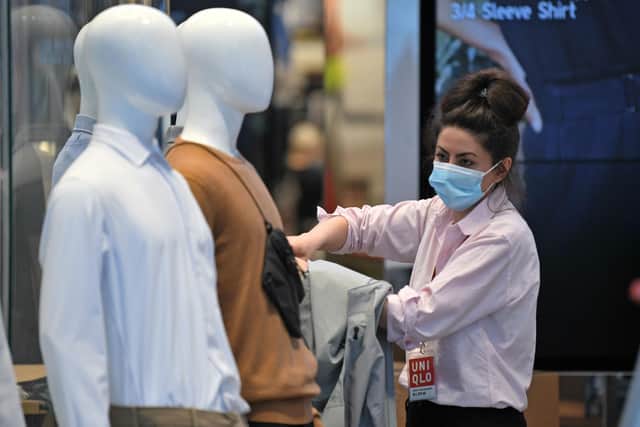 A Retail worker wearing PPE (personal protective equipment), including a face mask as a precautionary measure against COVID-19, works in the window display  (Photo by DANIEL LEAL-OLIVAS/AFP via Getty Images)