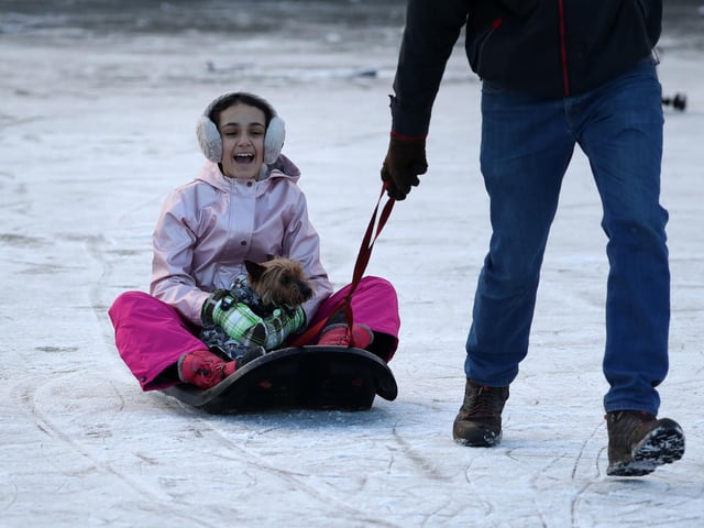 Guyatri Manak (11) with her dog Holly are pulled on a sledge along a frozen pond in Queen's Park in Glasgow. Picture: Andrew Milligan/PA Wire