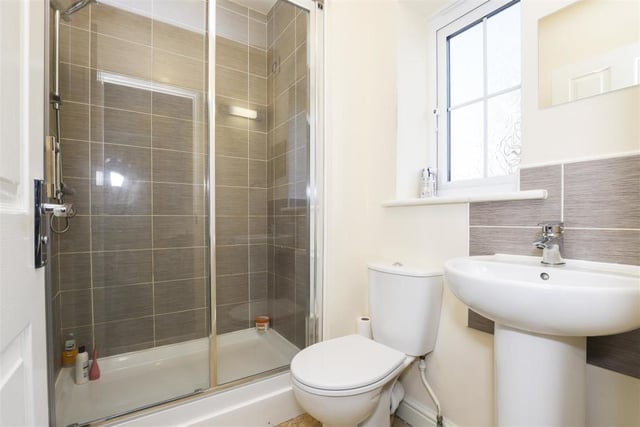 The en suite to the master bedroom features a shower enclosure with a wall-mounted shower, a low-level flush WC and a pedestal wash basin. The floor is tiled, as are some of the walls, while there is also a wall-mounted radiator, an extractor fan and a uPVC double-glazed, opaque window to the back.