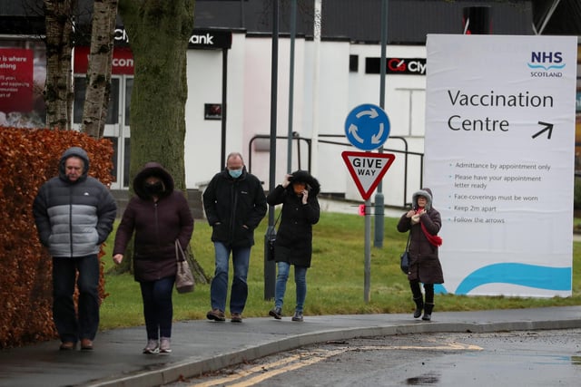 People walking by a Vaccination Centre sign at the Royal Highland Show ground in Edinburgh.