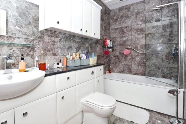 With a bath and matching white suite, this bathroom is tiled and offers good storage space.