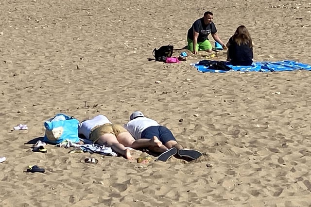 Two bathers enjoy a nap in the sun.