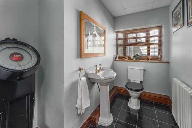 A large shower room with wooden flooring and a heritage-style suite comprising a pedestal wash hand basin and a white WC.