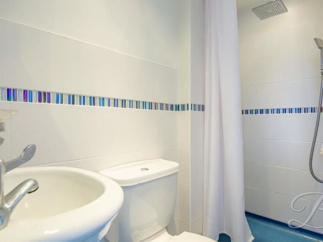 This is the en suite to the master bedroom. It includes a walk-in shower, low-flush WC and pedestal wash basin.