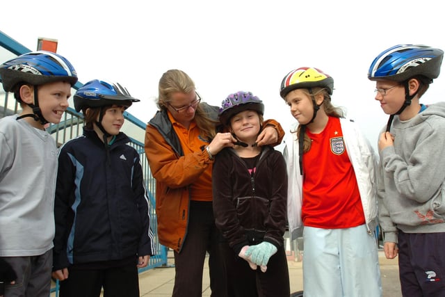 Cycle training instructor Sian Macarthur clips up the hat of pupil Chloe Howgarth as fellow cyclists Callum Gaety, Levan Robson, Sophie Molyneux and Daniel Gorman look on.