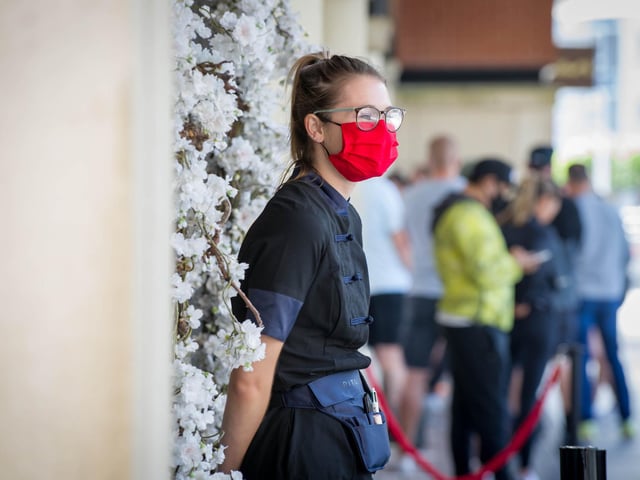 A shop worker outside Rituals wearing a protective face mask
