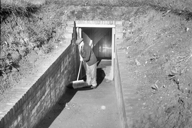 A workman does some sweeping up to keep this air raid shelter spotless.