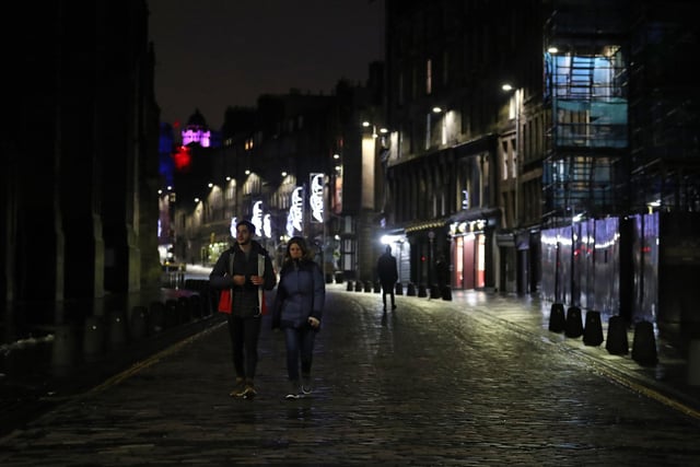 A couple walk along a quiet Royal Mile. Photo credit: Andrew Milligan/PA Wire
