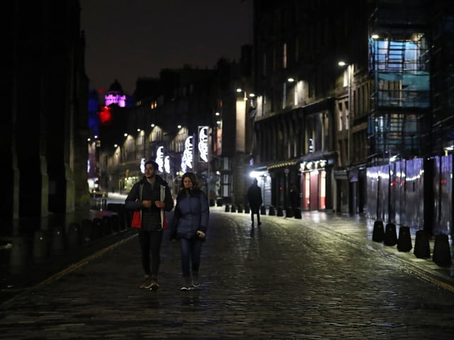 A couple walk along a quiet Royal Mile. Photo credit: Andrew Milligan/PA Wire