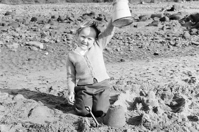 A little girl shows off her sandcastle on Portobello beach in July 1965 - technological advancements and factory working in the 1960s saw many people able to enjoy more leisure time