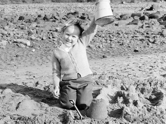 A little girl shows off her sandcastle on Portobello beach in July 1965 - technological advancements and factory working in the 1960s saw many people able to enjoy more leisure time