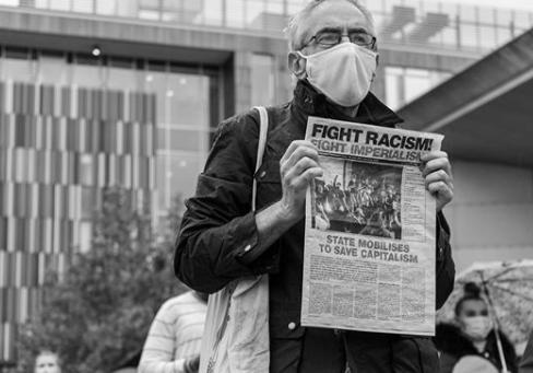A gentleman holding newspaper with headline "fight racism>"