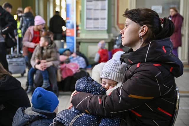 PRZEMYSL CITIES, POLAND - MARCH 23: A woman holds her baby as they wait at Przemysl train station before continuing their journey from in war-torn Ukraine on March 23, 2022 in Przemysl, Poland. Nearly two-thirds of the more than 3 million people to have fled Ukraine since Russia's invasion last month have come to Poland, which shares a 310-mile border with its eastern neighbor. (Photo by Jeff J Mitchell/Getty Images)
