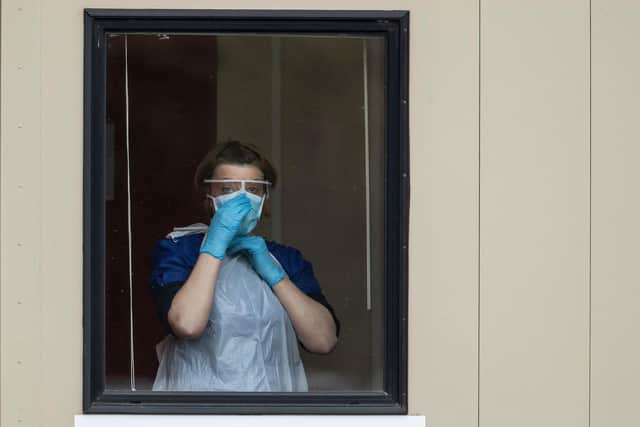 A nurse adjusts her face mask before taking swabs at a Covid-19 Drive-Through testing station for NHS staff. (Photo by Dan Kitwood/Getty Images)