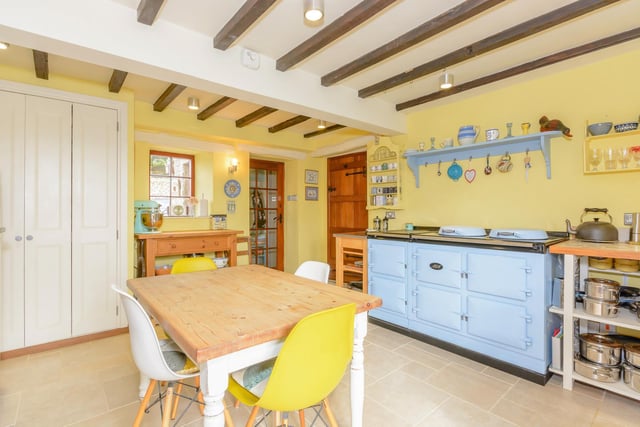 The kitchen has a light blue aga and beamed ceilings.