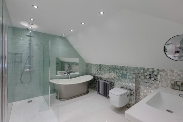 The contemporary family bathroom has a suite in white, a freestanding roll-top slipper bath and a large walk-in shower enclosure with fitted shower.