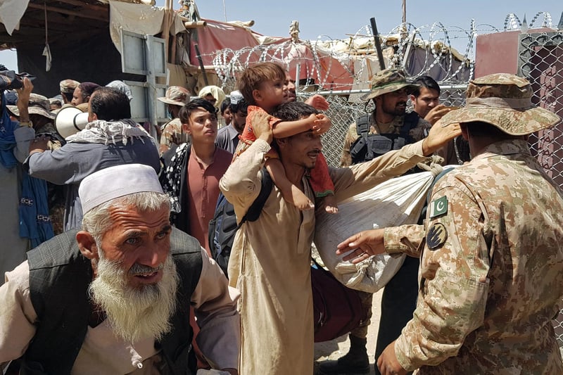 Pakistani soldiers (R) check stranded Afghan nationals at the Pakistan-Afghanistan border crossing point in Chaman