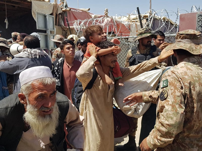 Pakistani soldiers (R) check stranded Afghan nationals at the Pakistan-Afghanistan border crossing point in Chaman