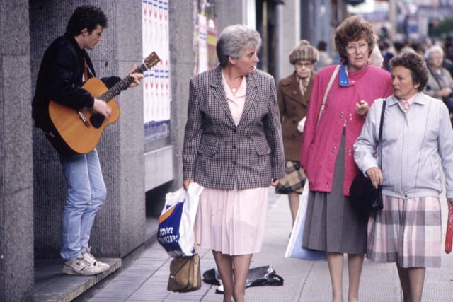 Women walk past a busker in Glasgow,  August 1990.