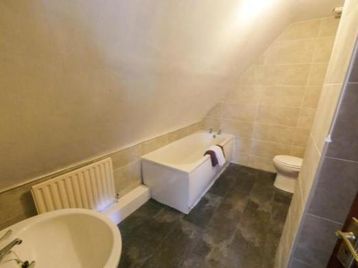 This spacious bathroom has a lovely white suite comprising low level wc, pedestal basin, and bath and is located on the first floor.