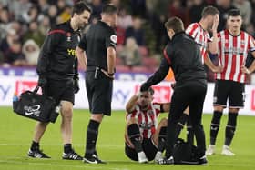 A dazed George Baldock of Sheffield United is helped to his feet during the match against QPR: Andrew Yates / Sportimage