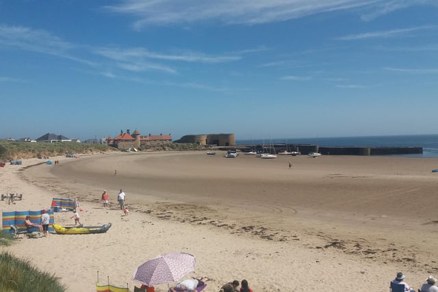 Visitors to Beadnell enjoying the sand with a view to the harbour.