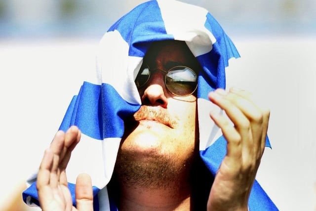 An Owls fan hiding from the heat claps the performance after Sheffield Wednesday's opening day win at Swindon in 2003
