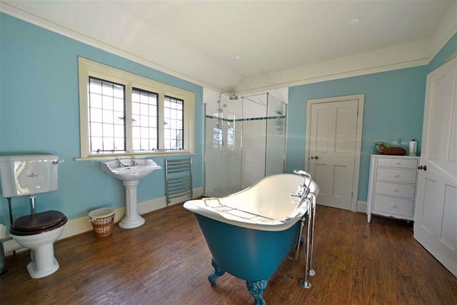 There are three bathrooms in total, including this generously sized bath and shower room with a slipper bath on ball and claw feet in the centre, alongside a ceramic tiled rain shower, wash basin and WC, and an open fireplace.