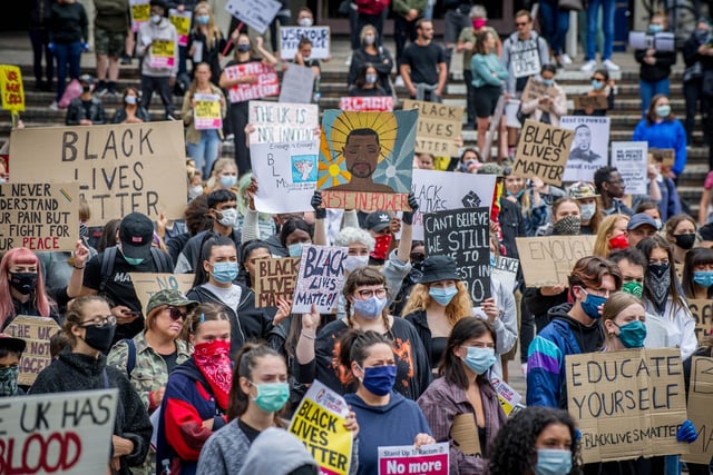 A sea of masked protestors unite bearing powerful messages.
