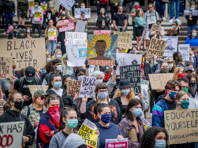 A sea of masked protestors unite bearing powerful messages.