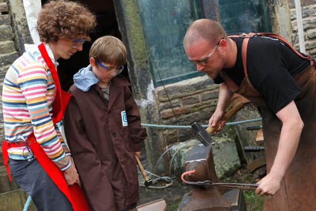 A family have a go at traditional skills at the blacksmith forge at Abbeydale Industrial Hamlet
