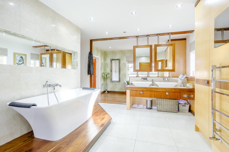 The property has four en-suites, this one features a bath, shower cubicle, wash basins and a TV