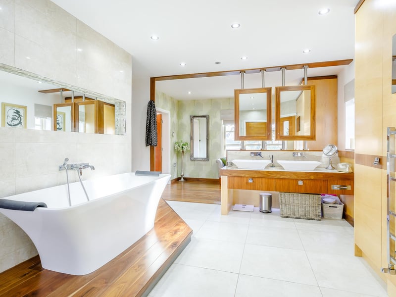 The property has four en-suites, this one features a bath, shower cubicle, wash basins and a TV