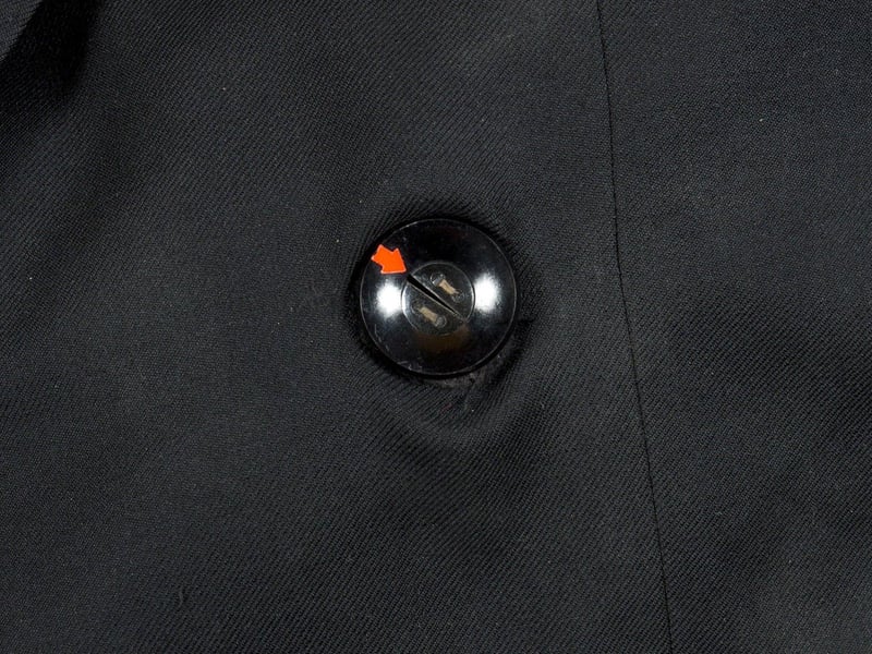Soviet KGB spy hidden camera designed to look like a coat button. Includes a hand operated shutter release mechanism and a coat for demonstration purposes. Estimate: $400-$600.
