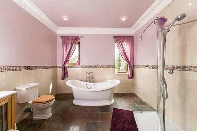 This en-suite is connected to the third bedroom (not pictured) located to the left of the property. It features a free standing bathtub, shower cubicle, wash basin and WC.