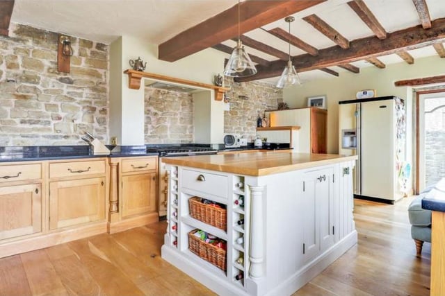 The kitchen features a central island, granite work surfaces, an inset Belfast sink, a duel-fuel Aga cooker and space for an American fridge freezer, all topped off by original ceiling beams.