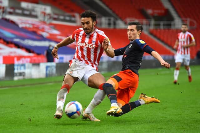 STOKE ON TRENT, ENGLAND - FEBRUARY 20: Jacob Brown of Stoke City is challenged by Dan Potts of Luton Town during the Sky Bet Championship match between Stoke City and Luton Town at Bet365 Stadium on February 20, 2021 in Stoke on Trent, England. Sporting stadiums around the UK remain under strict restrictions due to the Coronavirus Pandemic as Government social distancing laws prohibit fans inside venues resulting in games being played behind closed doors. (Photo by Nathan Stirk/Getty Images)
