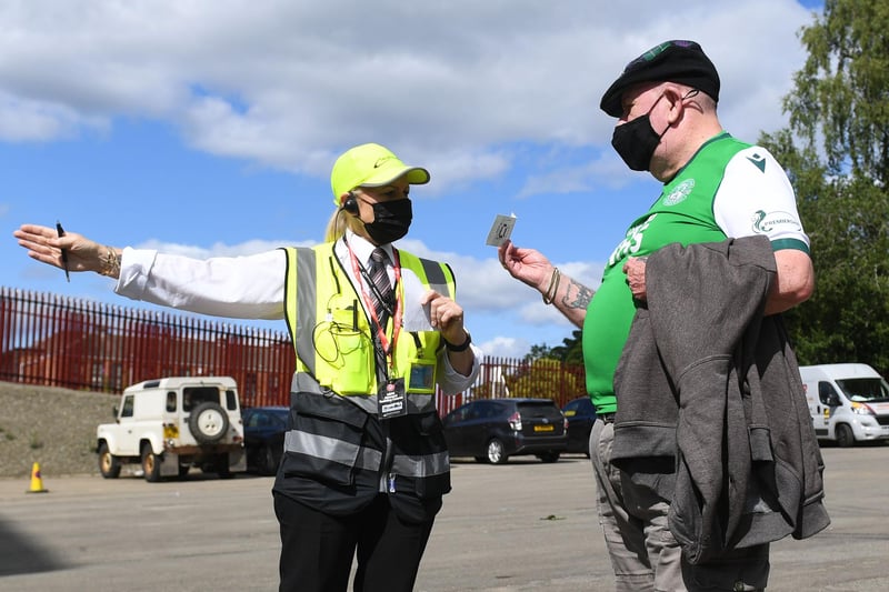 A Hibs supporter receives direction from a steward in the Fir Park car park